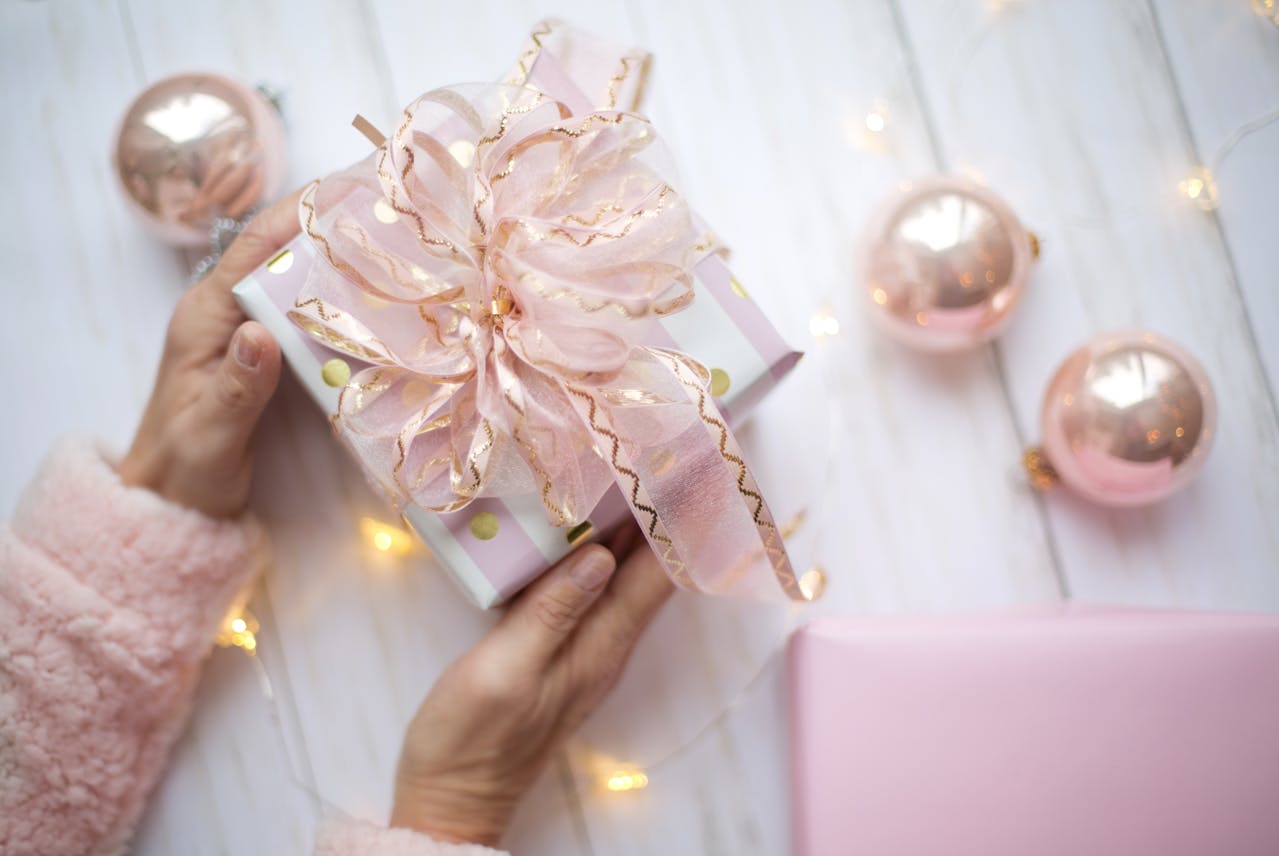 Delicate pink gift with ribbon for Mum with Dementia UK, surrounded by rose gold ornaments and soft lighting, creating a warm and comforting atmosphere